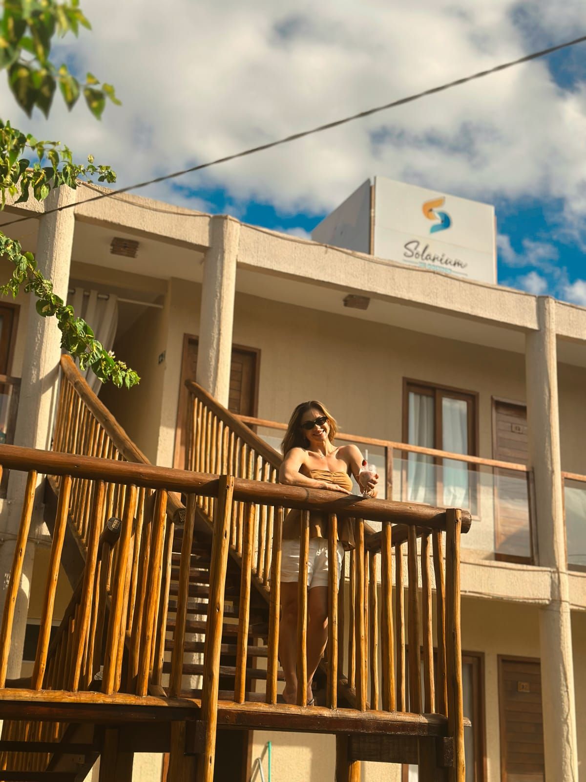 Una persona sentada en la barandilla de madera de un balcón de un edificio con un letrero que dice 'Solarium'.
