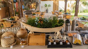 An outdoor dining area with wicker furniture, a central plant arrangement, and various food and drink containers.