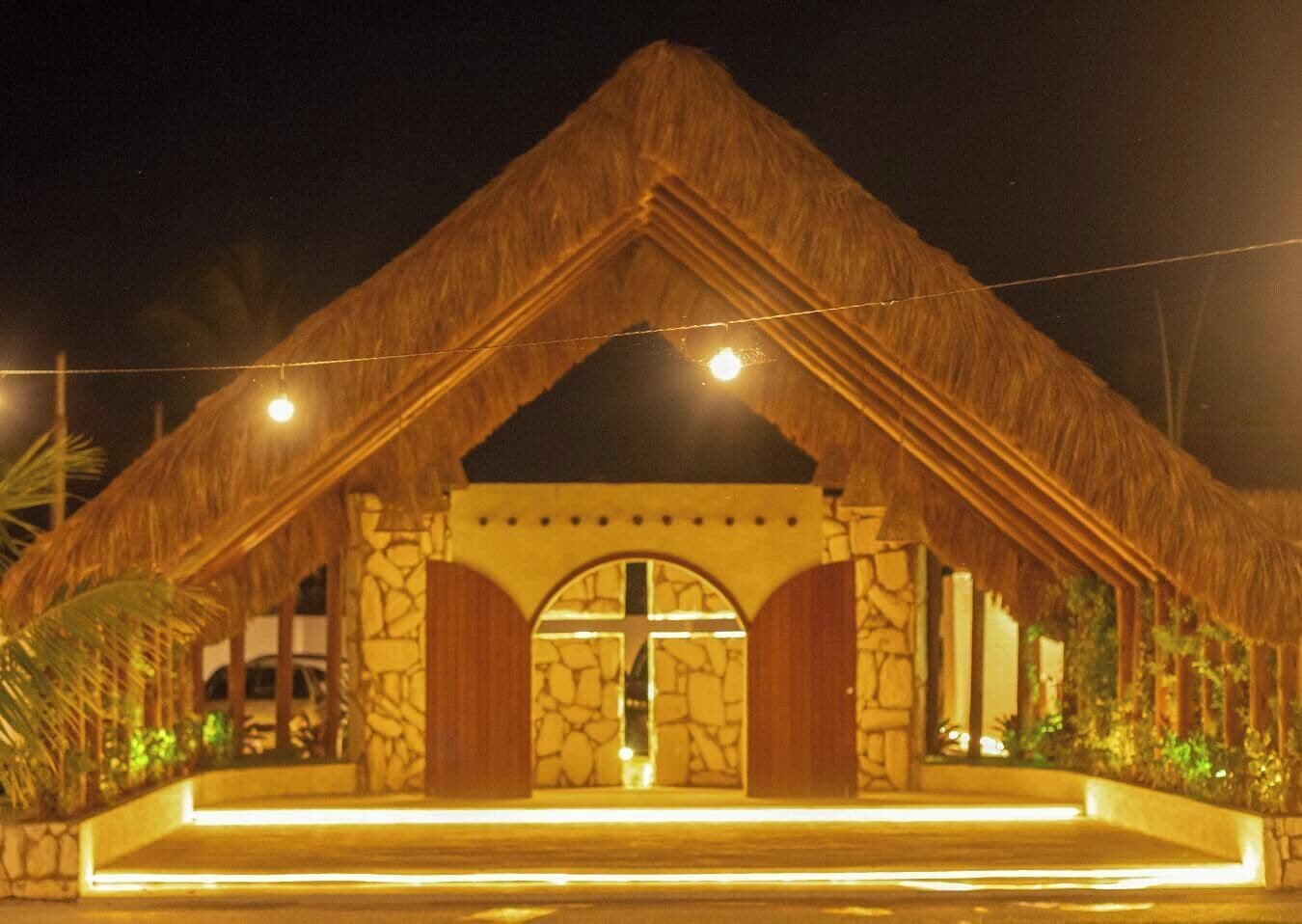 A building with a thatched roof, stone walls, and a central arched doorway.