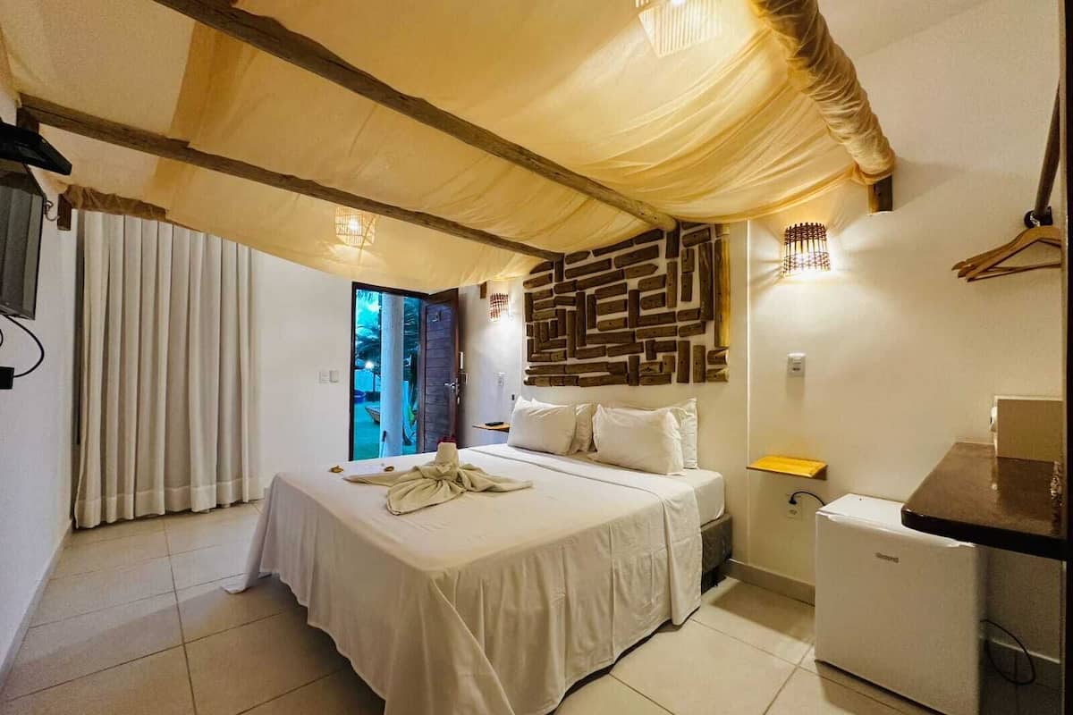 Ein Schlafzimmer mit Bett, einem kleinen Tisch, einem Kühlschrank und einer Wand mit geometrischem Muster.