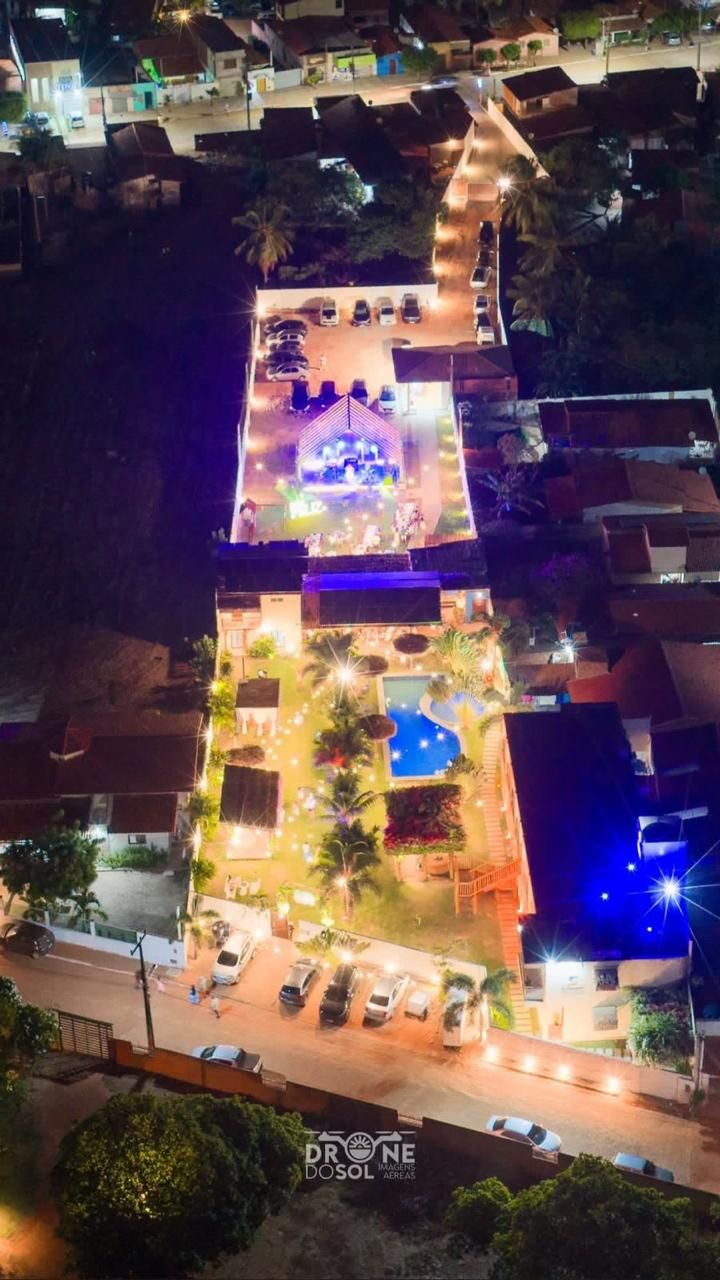 An aerial view of a hotel with a swimming pool, outdoor seating area, and multiple parking spaces.
