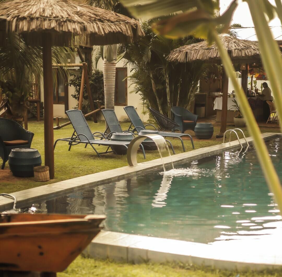 A pool area with lounge chairs and thatched umbrellas.