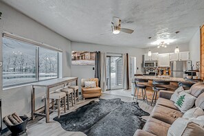 Un vaste espace de vie agrémenté d’une grande fenêtre, d’un ventilateur de plafond, d’une cuisine équipée d’appareils modernes et d’un coin salon confortable.