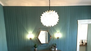 Ein Essbereich mit einem dunklen Holztisch, schwarzen Stühlen, einem gemusterten Teppich und teal-farbenen Wänden.