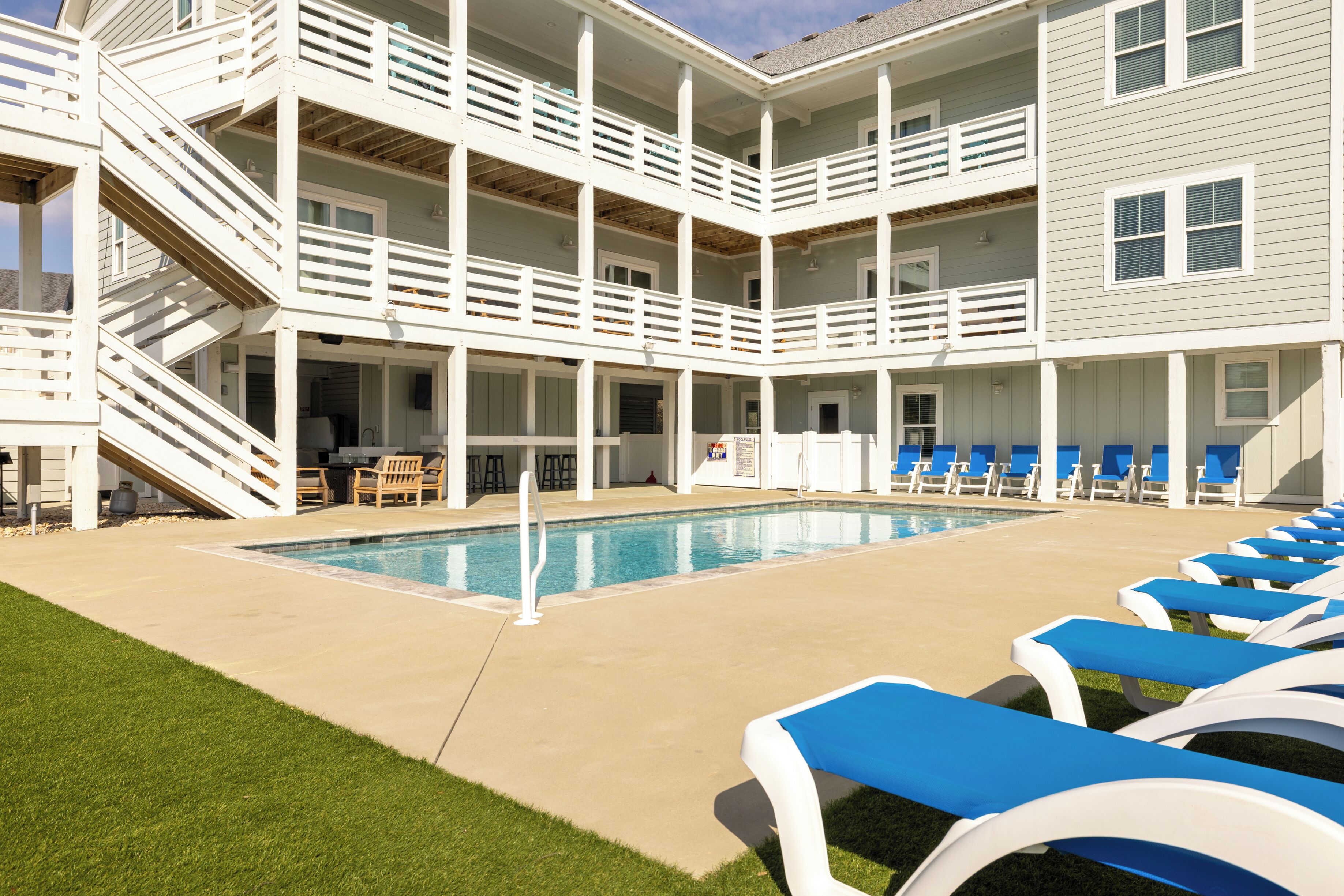 A multi-story building with a pool, outdoor seating, and a staircase.