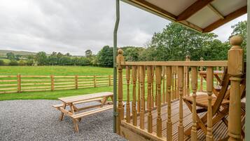 A wooden deck with a picnic table and a covered seating area.