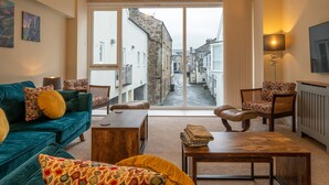 Ein gemütliches Wohnzimmer mit einem großen Fenster mit Blick auf eine enge Straße.