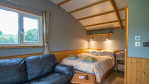 Una habitación acogedora con una cama, un sofá de cuero, una mesita de madera y una ventana con cortinas.