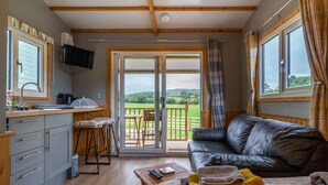 A cozy room with a kitchen, a sofa, a dining area, and a large sliding glass door leading to a balcony.