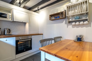 A kitchen with white cabinets, a wooden table, and a built-in oven.