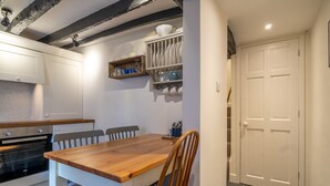 A kitchen with a wooden table, chairs, and a white door. - Low Nook Cottage -  Newly refurbished cottage for three guests (Broughton-in-Furness)