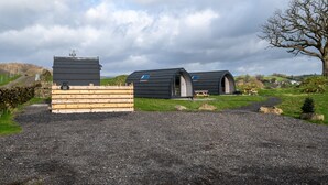 A modern, rustic building with a large wooden structure in the foreground and two dome-shaped cabins in the background.