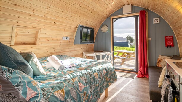 A cozy cabin room with a bed, a desk, a chair, and a large window.