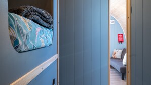A room with a bunk bed, a sofa, and a fire extinguisher on the wall.