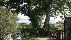 A stone wall, a grassy area, and a view of the sea.