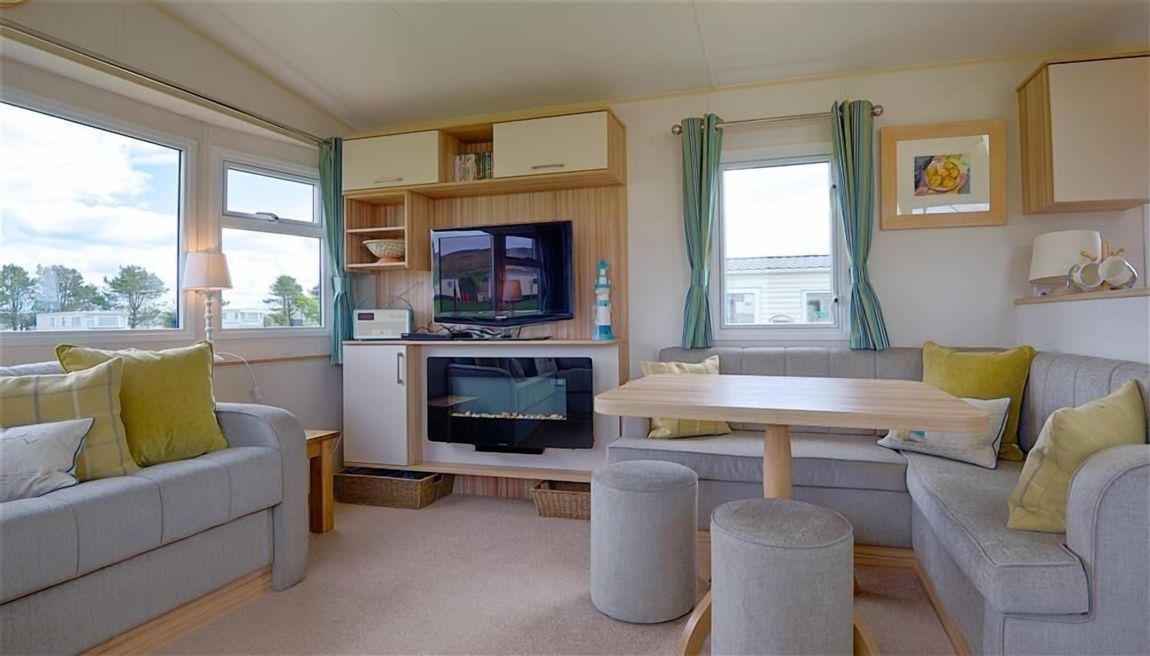 A compact living space with a sofa, a TV, a small table, and a window with curtains.
