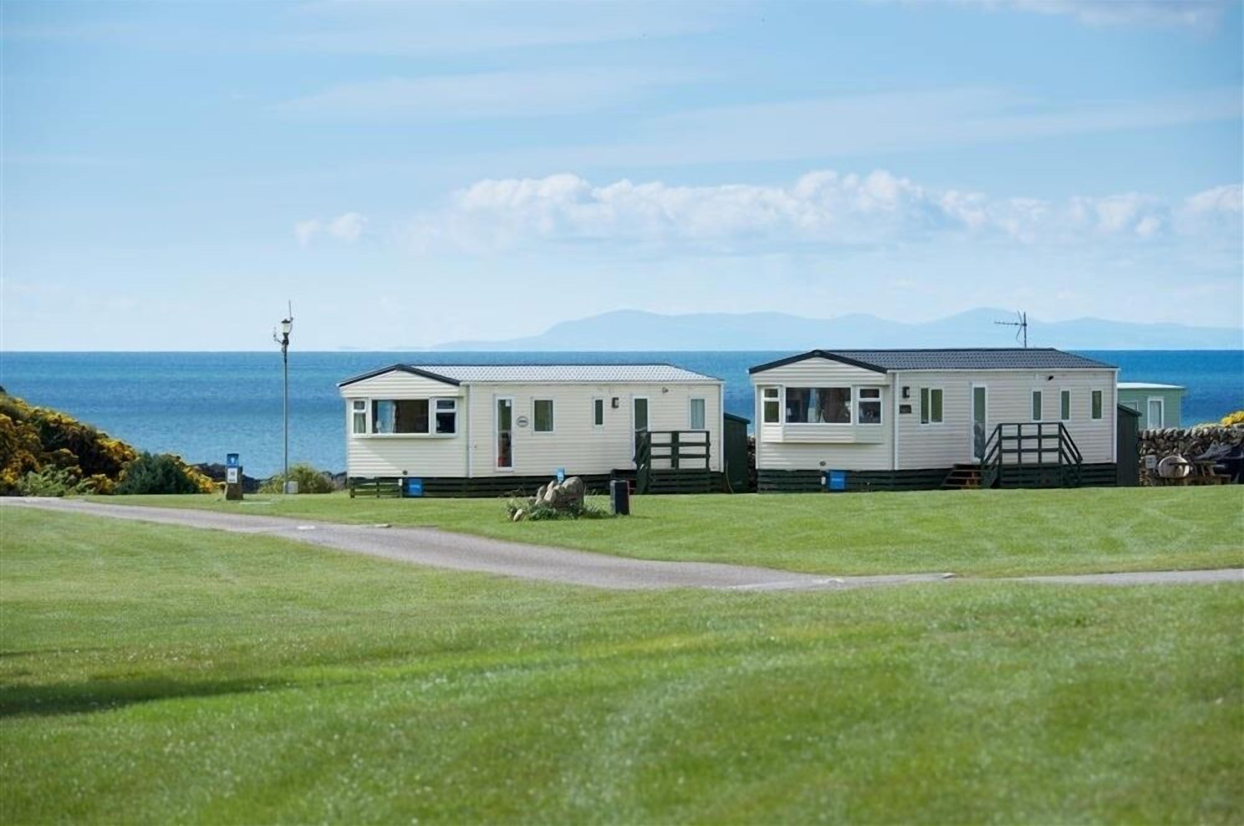 Two mobile homes with a view of the sea and mountains in the background.