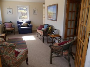A cozy living room with a blue sofa, a wicker chair, and a patterned armchair. - Sangobeag -  a cottage that sleeps 6 guests  in 3 bedrooms (Durness)