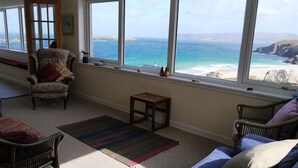 A room with a view of the sea, a chair, a sofa, and a small table. - Sangobeag -  a cottage that sleeps 6 guests  in 3 bedrooms (Durness)