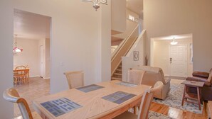 A spacious living room with a wooden dining table, comfortable seating, a staircase, and a chandelier. - Bright and Spacious Home in Quiet Neighborhood - ASTRP260664 (Colorado Springs)