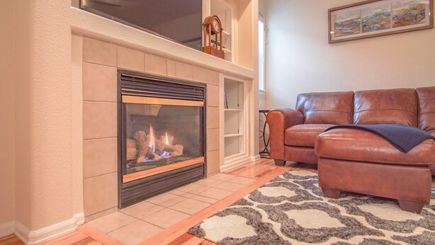 A living room with a fireplace, leather sofa, and a rug. - Bright and Spacious Home in Quiet Neighborhood - ASTRP260664 (Colorado Springs)