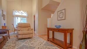 A spacious living room with a beige armchair, a wooden console table with a blue bowl, and a patterned rug. - Bright and Spacious Home in Quiet Neighborhood - ASTRP260664 (Colorado Springs)