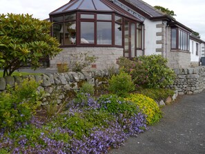 A stone building with a bay window and a stone wall with plants.