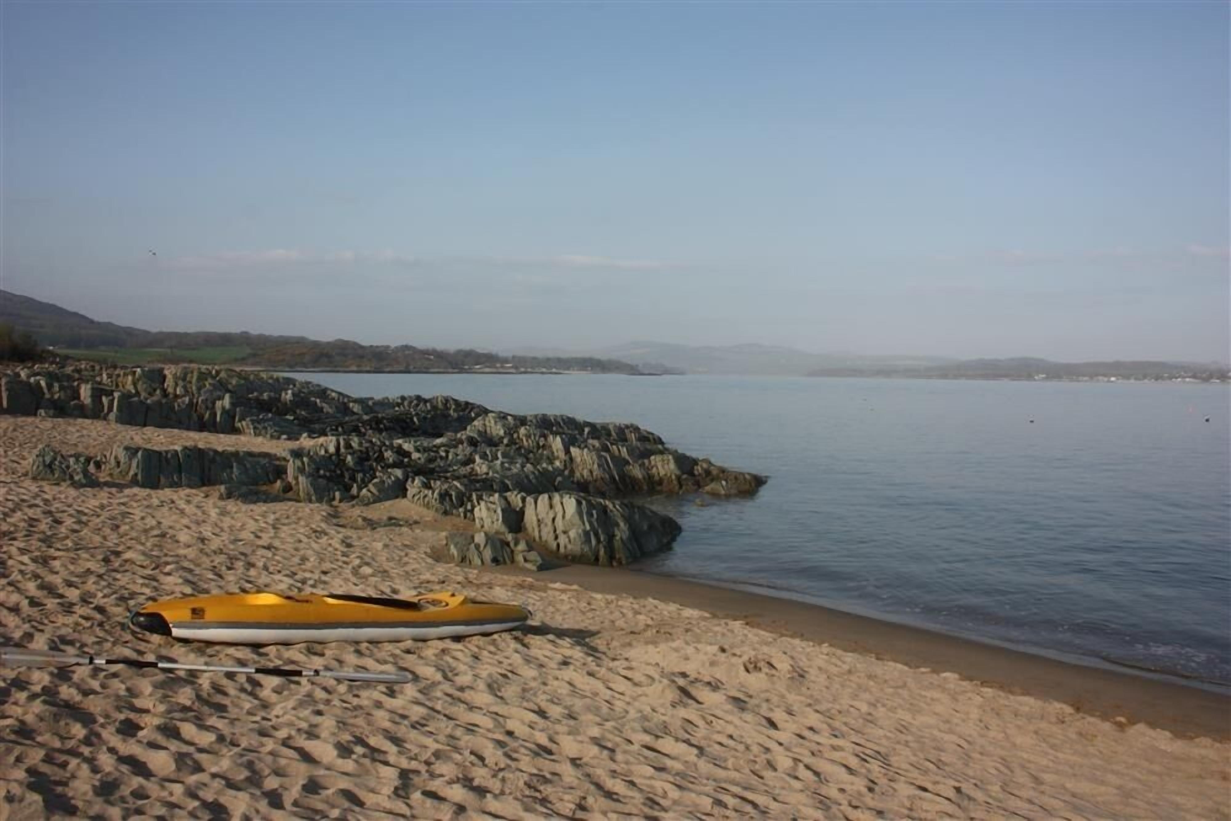 A beach with a kayak and a rocky shoreline.