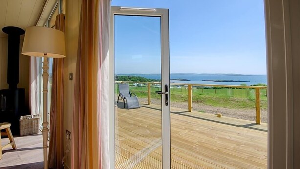 Une pièce dotée d’une grande porte-fenêtre coulissante donnant sur une terrasse avec vue sur la mer.