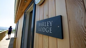 Un mur extérieur en bois sur lequel est apposée une enseigne indiquant « BARLEY LODGE ».