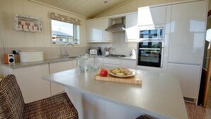 Une cuisine moderne avec des meubles blancs, un îlot central et un four encastré.