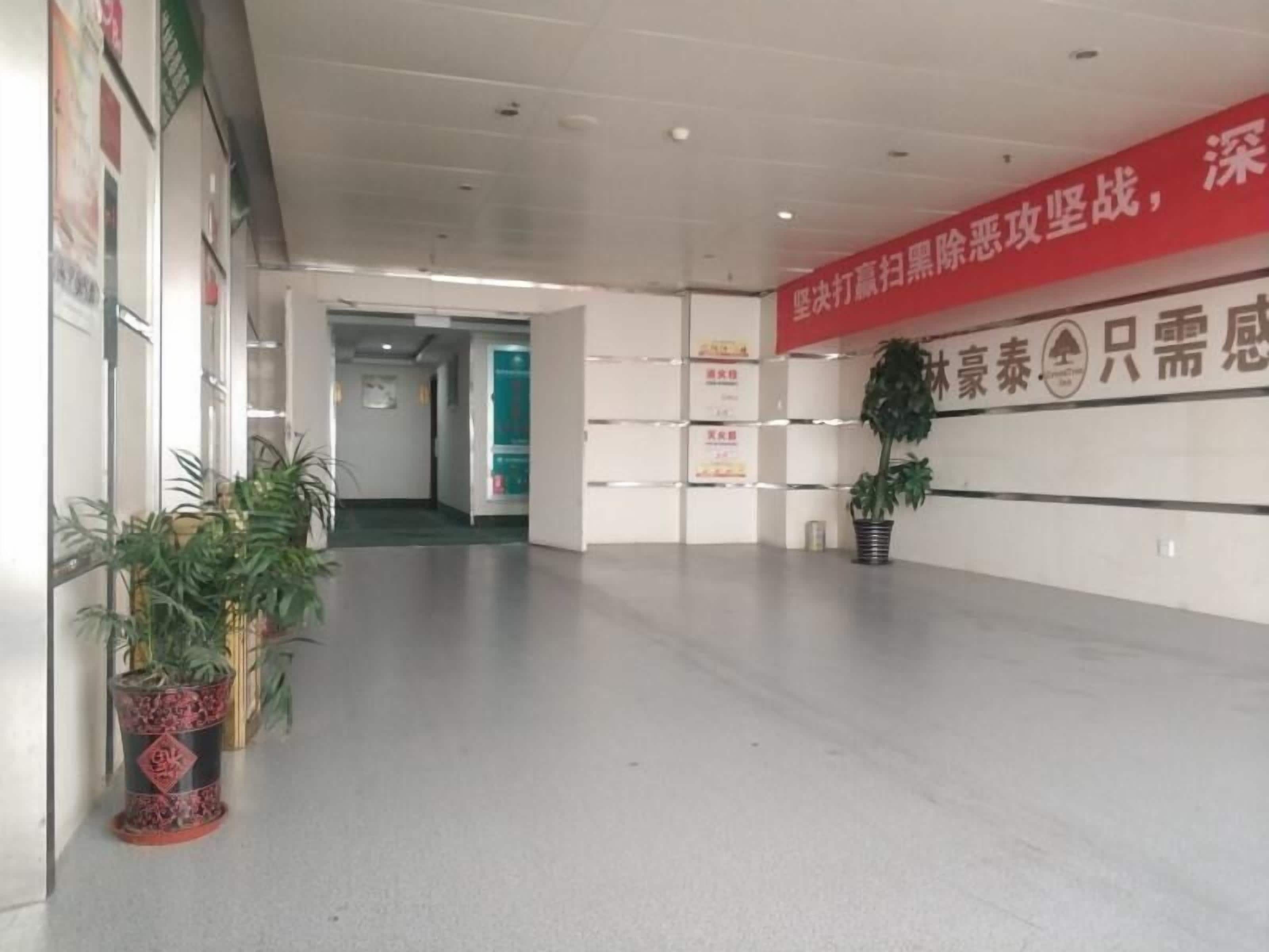 A hallway with a red banner, potted plants, and a sign on the wall.