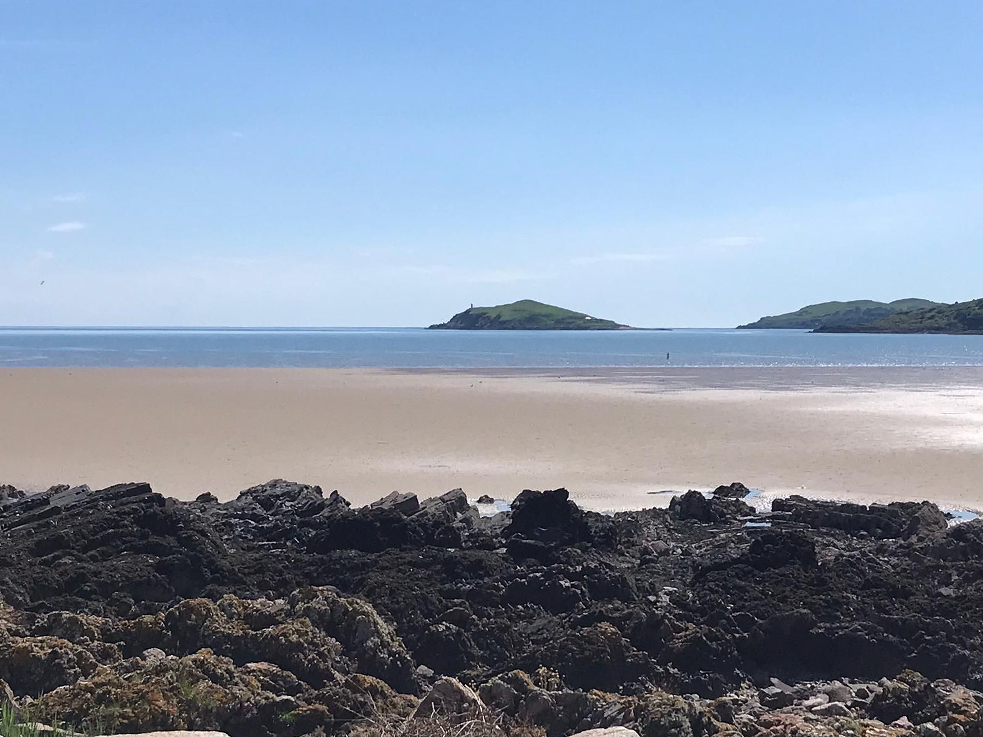 A beach with rocky foreground and calm sea.