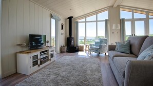 Un salón amplio con televisor grande, chimenea y vistas al exterior.