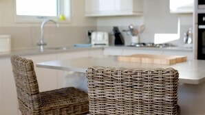 Una cocina con una isla central, un lavaplatos y una silla.