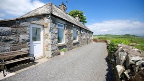 A stone cottage with a gravel driveway and a bench outside. - Threaby Cottage -  a cottage that sleeps 4 guests  in 2 bedrooms (Gatehouse of Fleet)