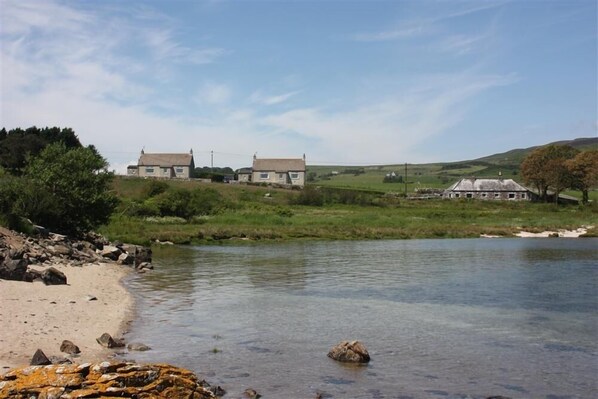 Vista al río con dos casas y una playa de arena.