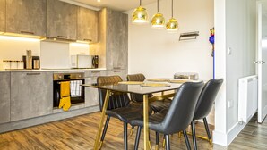 A modern kitchen with a dining area, featuring a large table, chairs, and pendant lights.