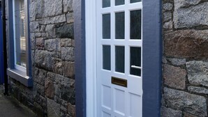 Un bâtiment en pierre avec une porte blanche et une fenêtre.