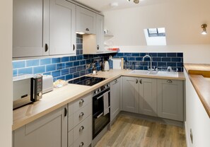Una cocina moderna con armarios grises, encimera de madera, horno empotrado y un lavabo.