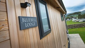 A wooden exterior wall with a sign reading "BLUEBELL LODGE" and a window.