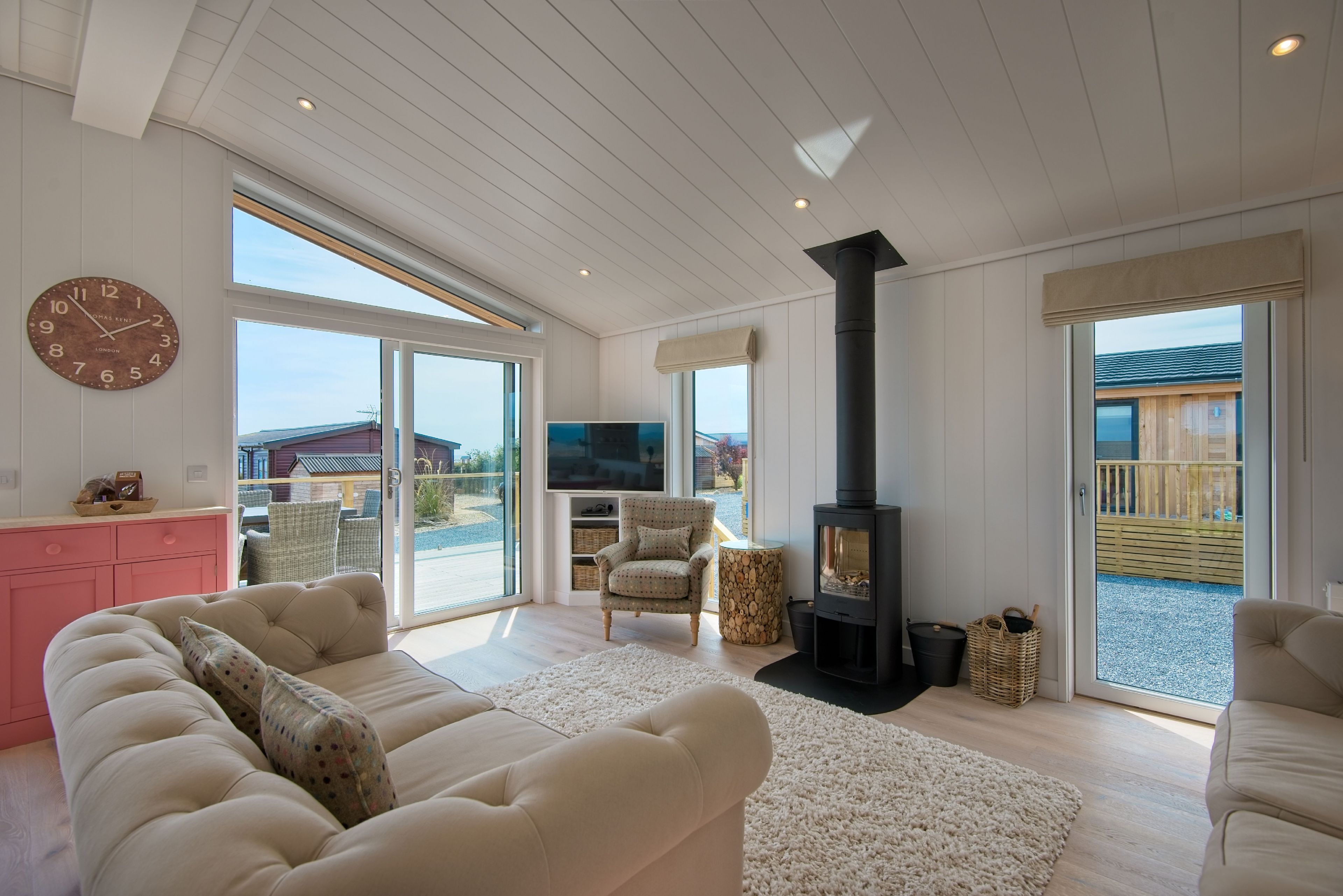 Un salón amplio con un sofá grande, televisor, chimenea y puerta corrediza de vidrio que da a una terraza.