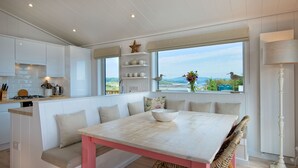 A modern kitchen with white cabinetry, a pink table, and a large window with a view of the outdoors. - Clover Lodge -  a lodge that sleeps 6 guests  in 3 bedrooms (Gatehouse Of Fleet)