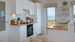 A modern kitchen with white cabinetry, a wooden countertop, and a view of the outdoors. - Clover Lodge -  a lodge that sleeps 6 guests  in 3 bedrooms (Gatehouse Of Fleet)