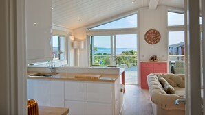 A modern kitchen with a large island, a pink cabinet, and a view of the outdoors. - Clover Lodge -  a lodge that sleeps 6 guests  in 3 bedrooms (Gatehouse Of Fleet)