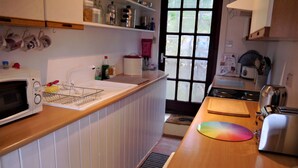 Une cuisine équipée d’un four à micro-ondes, d’un évier et d’un plan de travail en bois. On y trouve des placards au-dessus du plan de travail et une fenêtre donnant sur l’extérieur.
