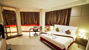 A hotel room with a large bed, a desk with a chair, a small table, and a wardrobe. - Grand Citra Hotel Makassar By Life (Makassar)