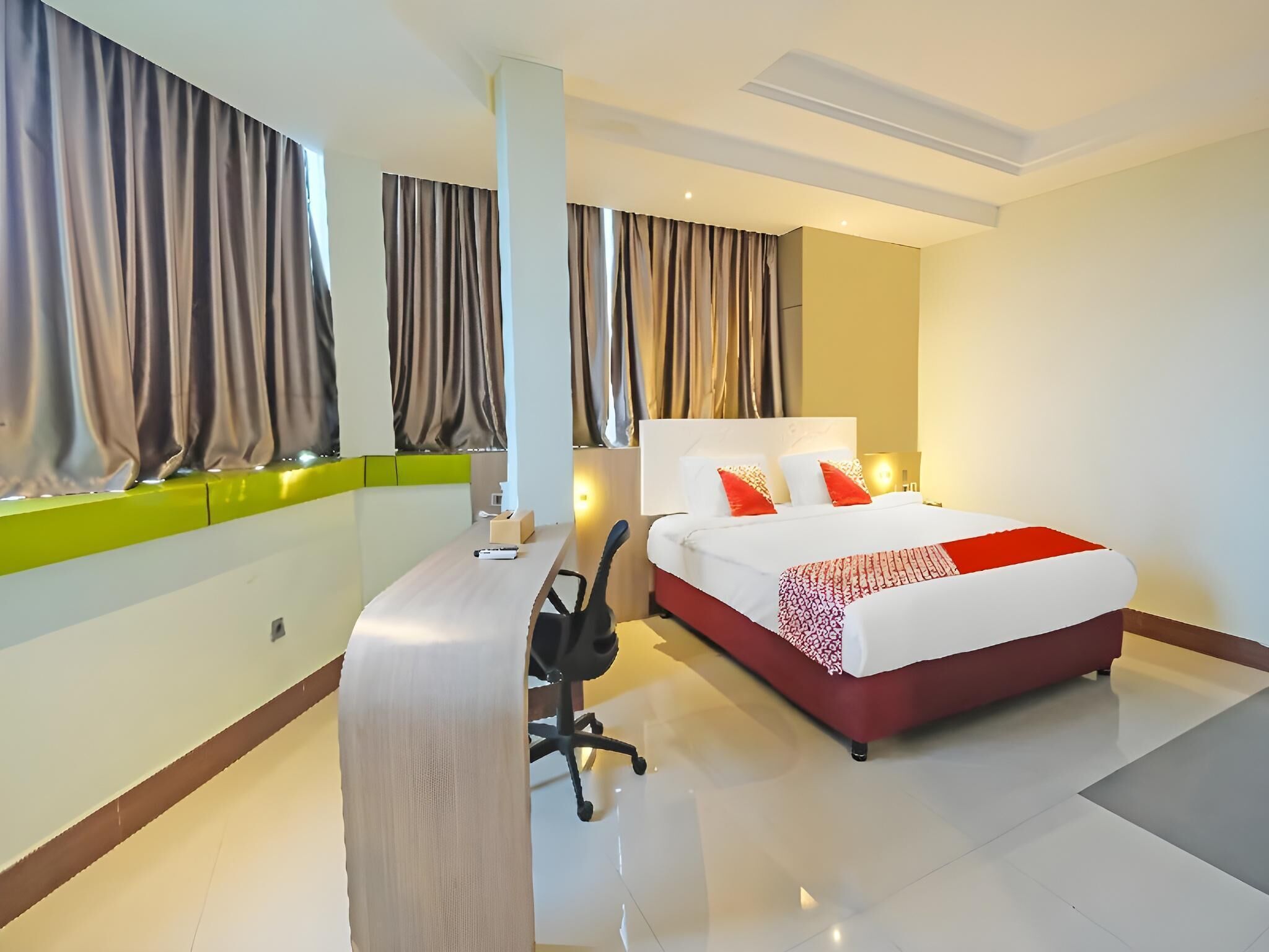A modern hotel room with a bed, a desk, a chair, and a window with curtains.