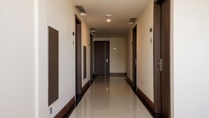 A hotel hallway with wooden doors, a tiled floor, and recessed lighting. - Grand Citra Hotel Makassar By Life (Makassar)
