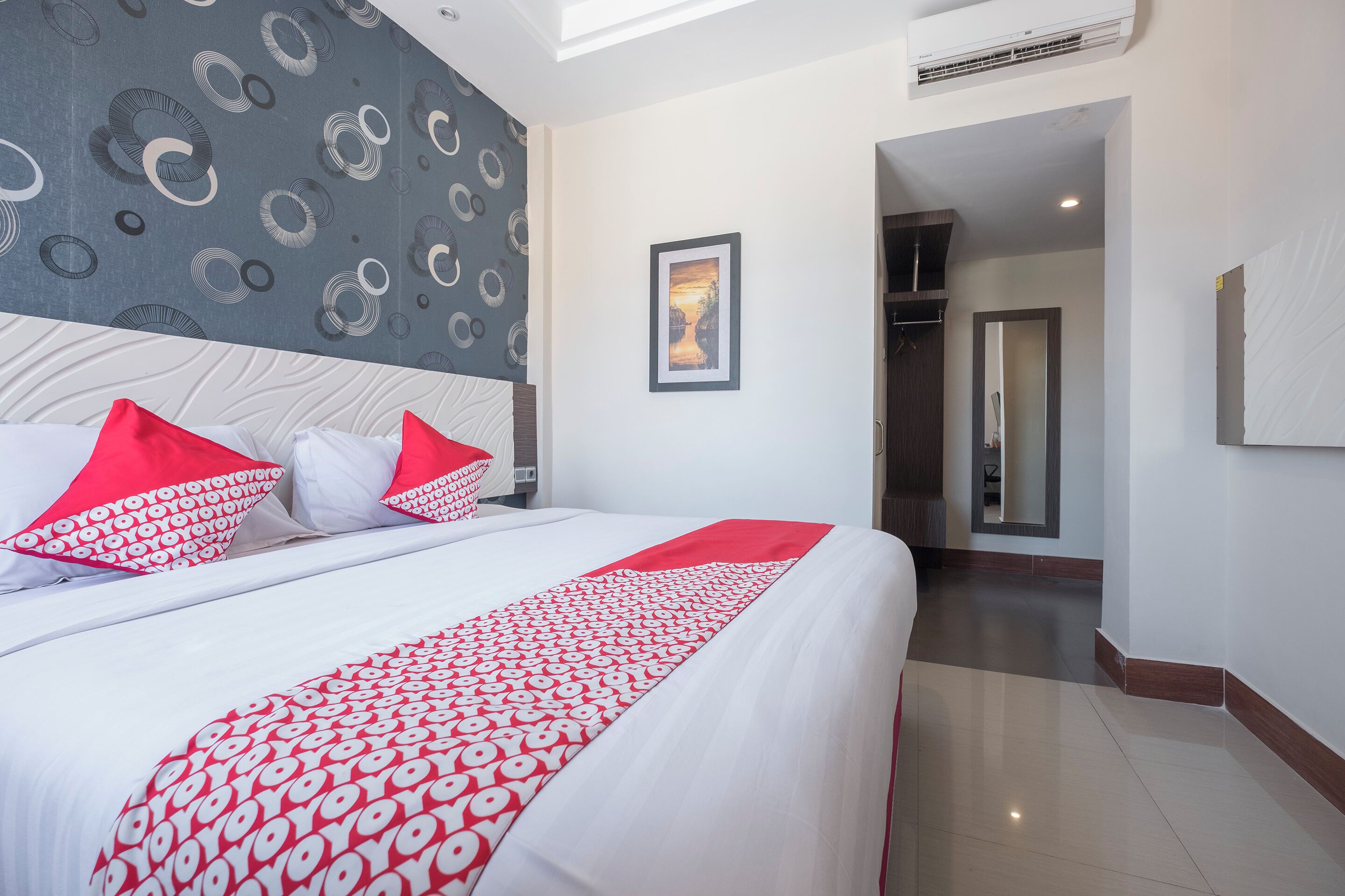 Una habitación de hotel con una cama grande, un papel tapiz estampado y un cuadro en la pared.